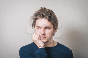 young man thinking, daydreaming deeply about something, hand on chin