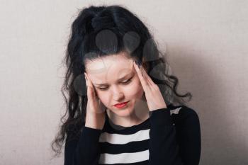 Woman with long hair put her hands on her head, headache. Gray background