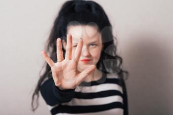 A woman shows a hand, hello. Gray background