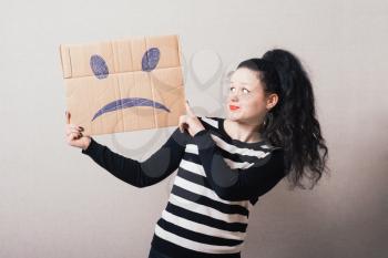 Woman brown cardboard with a sad smiley. Gray background