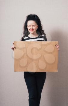 A woman holds a blank kraft paperboard. Gray background