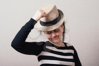 Woman takes off his hat and clothes. Gray background.