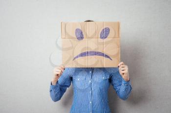 Young woman standing with a cardboard on his head with sad face