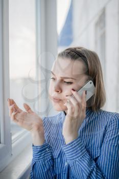 Business woman speaking phone and looking through window with city background
