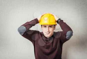 man close-up in yellow helmet headache, holding his head by hand