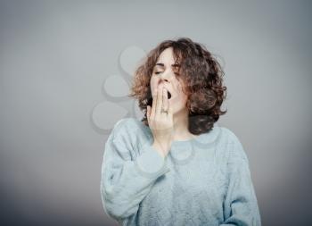 Closeup portrait of a pretty sleepy young woman placing hand on mouth yawning and looking at you bored, isolated white background. Negative human emotion facial expression feelings, sign and symbols