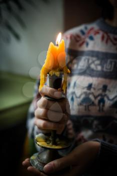 hands hold a candlestick with a candle