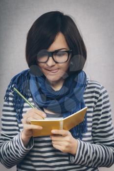 young woman in glasses writes something in a notebook