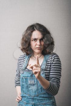 A woman has the index finger careful stop. On a gray background.