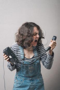 Young woman   yelling at telephone handset that she is holding in her hand