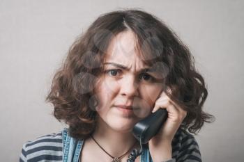 Young woman   yelling at telephone handset that she is holding in her hand