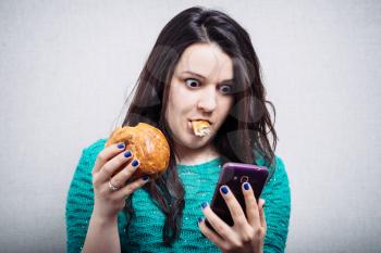cute girl eating a muffin and holding a phone