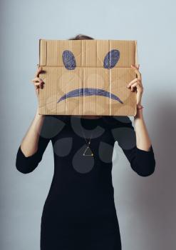 Young woman standing with a cardboard on his head with sad face