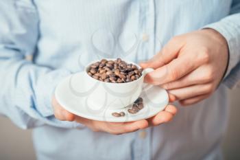 Cup of coffee beans. Young man holding a cup of coffee beans in his hands.