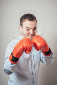Businessman ready to fight with boxing gloves over gray background. Looking at camera