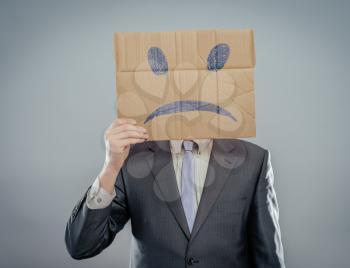 Putting a smiling face on. Man holding cardboard paper with smiley face printed on as sadness sorrow.