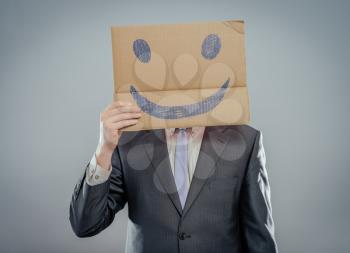 Putting a smiling face on. Man holding cardboard paper with smiley face printed on as happiness and joy concept.