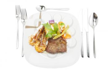Grilled steak and shrimp served on mashed potatoes with vegetables.
