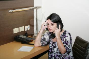 Stressed businesswoman holding her forehead while speaking on the telephone