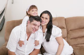 Embracing a happy family with child at home and expectant mother