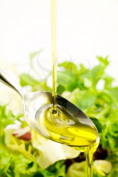 Royalty Free Photo of Pouring Oil on a Spoon With Greens Behind