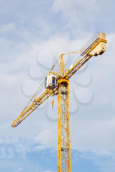 Yellow stationary hoist crane in sunlight.