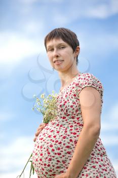 Royalty Free Photo of a Pregnant Woman Holding a Chamomile Bouquet 
