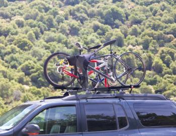 Three bicycles on the top of offroad car near forest
