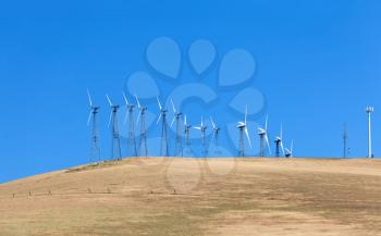 Set of windmills on the cornfield with blue sky in California
