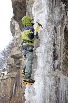 Man with ice axes and crampons climbing on icefall
