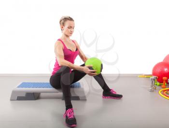Athletic young woman training with green ball in the gym
