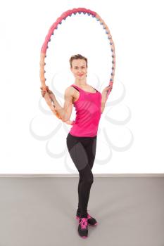 Athletic young woman with hula hoop isolated on white
