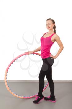 Athletic young woman with hula hoop in the gym
