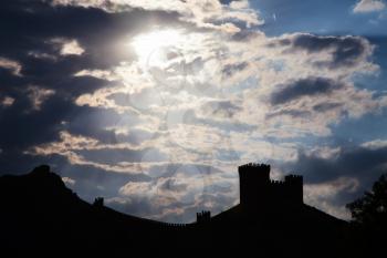 Genoese fortress silhouette with blue sky and clouds at sunset
