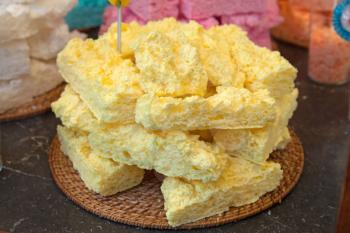 Yellow meringue cakes in pile on the wooden straw dish