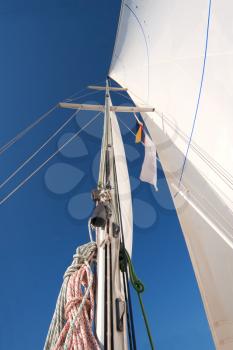 Yacht mast with ropes and sailing in blue sky