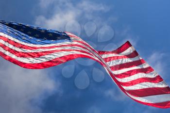 USA flag waving on the wind on cloudy sky background