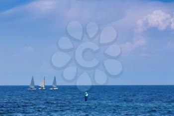 Three sailing centerboarder in open blue sea and fisherman
