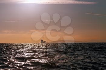 Bulk-carrier ship sailing in the sea at sunset
