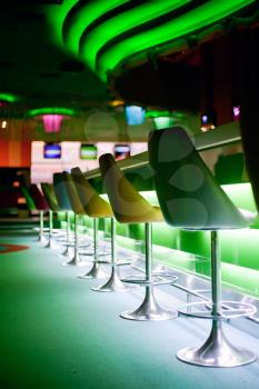 Chairs in row in bar with green lights

