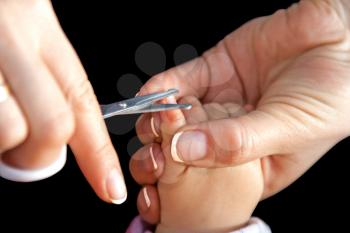Mother cutting nails with scissors isolated on black
