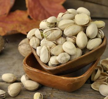 Royalty Free Photo of Cracked and Dried Pistachio Nuts In A Wooden Bowl