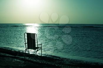 Royalty Free Photo of a Chair on a Beach at Sunset