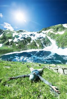 Royalty Free Photo of a Boy Laying in Grass by a Mountain