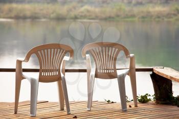 Royalty Free Photo of Patio Chairs on a Deck Overlooking Water