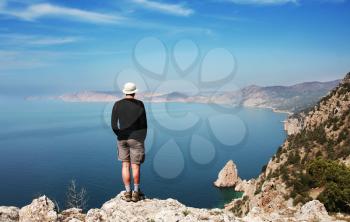 Royalty Free Photo of a Man Standing on a Rock Looking at the Ocean