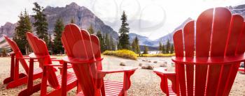 Red comfortable deck chairs on the lake in Canada. Canadian travel concept. Banner size