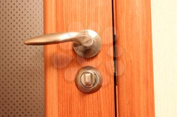 The metal handle and wooden door close up