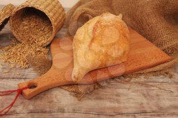 Homemade baked wheaten bread on wooden background with grains