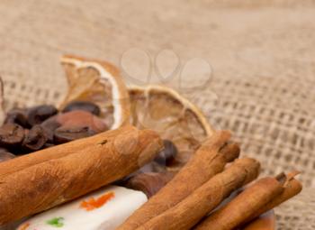 Sweets, cinnamon, nuts and coffee beans on a saucer, on burlap background.